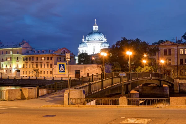 Vista nocturna de la Catedral de la Trinidad detrás de los edificios y el puente Krasnoarmeysky — Foto de Stock