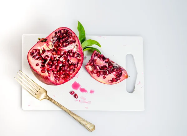 Pomegranate seeds and green leaves on the white background — Stock Photo, Image