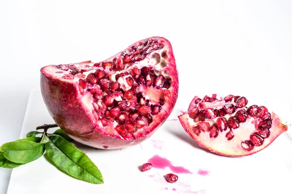 Pomegranate seeds and green leaves on the white background — Stock Photo, Image