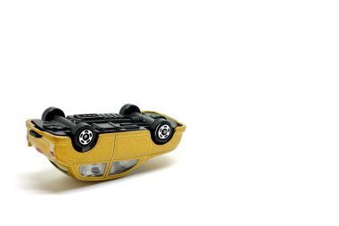 Golden toy car overturned on a white background clipart