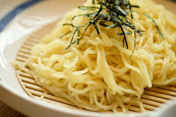 Noodles sprinkled with seaweed on the plate — Stock Photo, Image