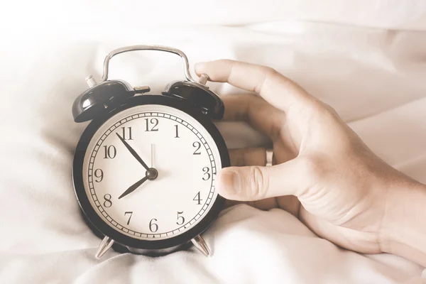 Relógio despertador com as mãos segurando um relógio — Fotografia de Stock
