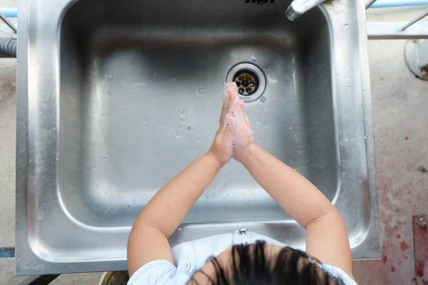 La chica se lava las manos. Imagen de archivo