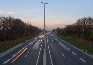 Trafik, araba ile ışık rotaları karayolu üzerinde gün batımında