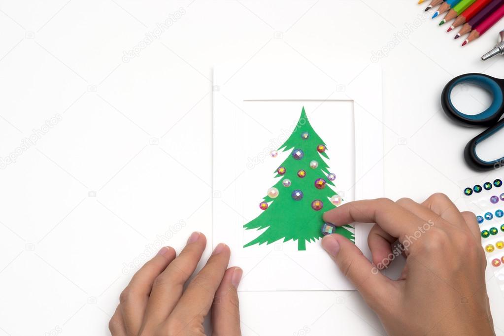 Girl is decorating Christmas card. Handmade
