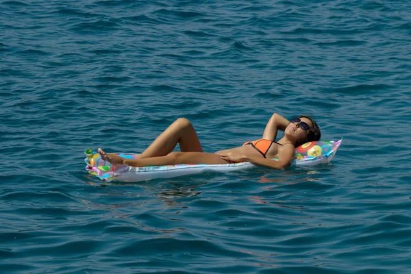 Femme sur matelas gonflable dans la mer Image En Vente