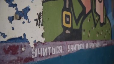 Duvarda eski bir çizim, yeşil elbiseli bir adam ve bir kız, arka planda bir roket. Terk edilmiş okul / cephe manzarasının aşağıdan yukarıya / Rusya 