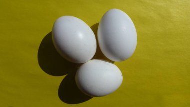 Sarı arka planda üç beyaz yumurta.