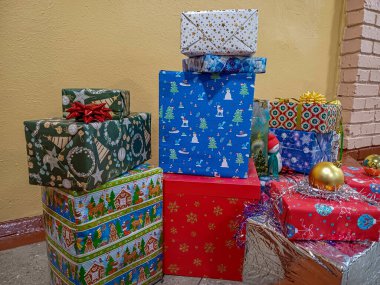 çeşitli hediye kutuları, güzelce paketlenmiş, kurdelelerle süslenmiş, Noel ağacındaki katman, oyuncak kardan adam, yeni yıl ambalajları, sarı arka plan, gümüş yağmur, Noel, kutlama, tatil, yatay fotoğraf,