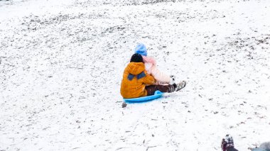 Çocuklar kızakla kayıyor, lolipoplar, kızlar, erkekler, kış, ilk kar, eğlence, kar, tatil, yeni yıl, uzak plan
