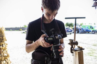 Kahverengi gözlü, kameralı bir gencin portresi, çekler çekiliyor, ekrana bakıyor, fotoğraf çekiyor.,