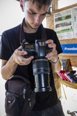 Kahverengi gözlü, kameralı bir gencin portresi, çekler çekiliyor, ekrana bakıyor, fotoğraf çekiyor.,