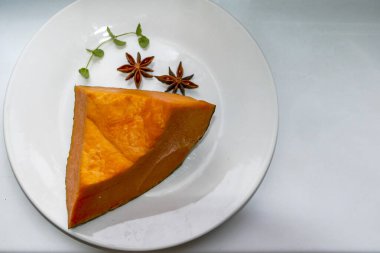 Beyaz tabakta bir parça balkabağı, balkabağı meyvesi, baharat, portakal sebzesi, nane filizi, mikro yeşil, yakın plan, zengin renk, iç posa, taze, sağlıklı yiyecek, olgun meyve, kesik, vegan yemeği, kahvaltı, üst manzara, makro, yatay fotoğraf