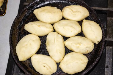 Kızartma tavasında yağda kızartılmış turtalar, ham hamur, yağda kızartılmış, altın hamuru, popüler Ukrayna yemeği, maya hamuru, dolgu, patates, lahana, et, mutfak, kızartma, yakın çekim, yatay fotoğraf,