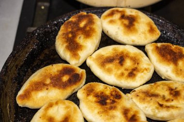 Kızartma tavasında yağda kızartılmış turtalar, altın kabuk, popüler Ukrayna yemeği, maya hamuru, dolgu, patates, lahana, et, mutfak, kızartma, yakın çekim, yatay fotoğraf,