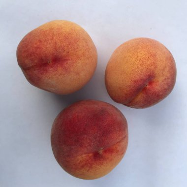 beyaz zemin üzerinde üç olgun şeftali 