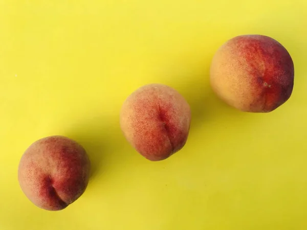 Drei Reife Pfirsiche Auf Gelbem Hintergrund — Stockfoto