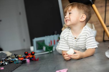 İki yaşında tatlı bir çocuk, aydınlık ve rahat bir odada mutlu bir şekilde oynuyor. Bebek enerji ve merakla dolu, yaratıcı oyunlardan hoşlanıyor ve yeni şeyler keşfediyor. Çocukluğu, erken öğrenmeyi ve aile hayatını resmetmek için mükemmel bir görüntü.