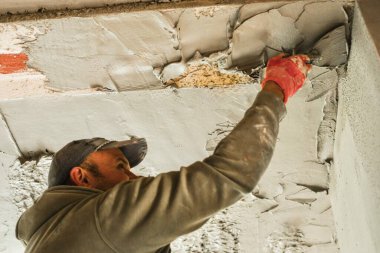 Tuğladan duvarları olan bir binanın iç tadilatı sırasında tavanı alçılayıp düzleştiren iki inşaat işçisi. Profesyonel müteahhitler sıva başvurusu ve duvar kaplaması üzerinde çalışıyor. İnşaat, onarım ve ev geliştirme kavramı.