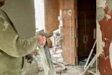 İnşaat işçisi, tadilat sırasında tuğla bir duvara malayla sıva uyguluyor. İş kıyafetleri içinde bina duvarına çimento sıva yapıştıran bir inşaat işçisi. İnşaat, ev onarımı ve iç dekorasyon kavramı.