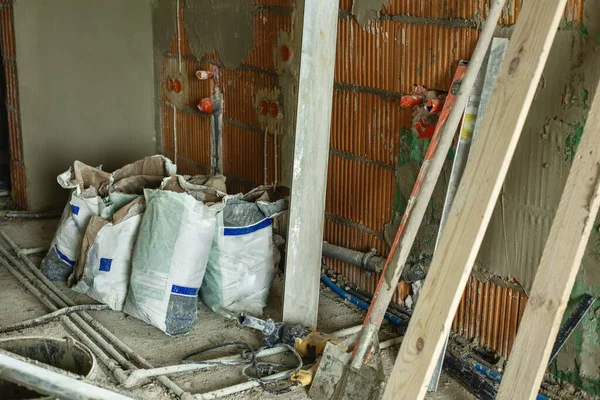 Çimento, macun ve diğer inşaat aletleriyle dolu çantalar tadilat sırasında odada duruyor. İnşaat malzemeleri, iç onarım ve ev geliştirme süreci kavramı. 