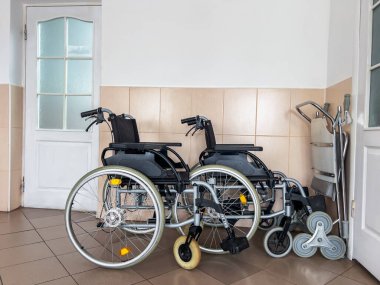 Hastane koridorunda kapının yanında boş tekerlekli sandalyeler ve hareketlilik cihazları var. Erişilebilirliği, hasta bakımını, iyileşmeyi ve tıbbi desteği sembolize eden sağlık ve rehabilitasyon kavramı. 