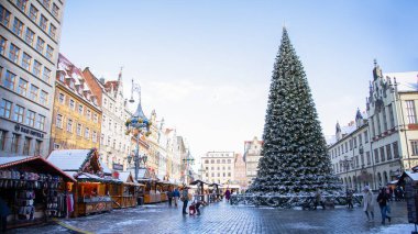Polonya 'nın Wroclaw kentindeki tarihi Pazar Meydanı' nda kış Noel pazarı, süslü ahşap tezgahlar, dev bir Noel ağacı, şenlikli atmosfer ve karla kaplı çatılar..