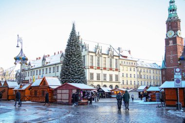 Polonya 'nın Wroclaw kentindeki tarihi Pazar Meydanı' nda kış Noel pazarı, süslü ahşap tezgahlar, dev bir Noel ağacı, şenlikli atmosfer ve karla kaplı çatılar..