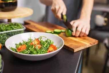 Mutfakta salatalık doğrayan mutlu genç çocuk taze sebze salatası hazırlıyor. Sağlıklı yaşam tarzı konsepti, otantik.