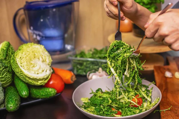 Genç çocuk taze sebze salatası hazırlıyor roka, salatalık ve domates mutfakta, sağlıklı yaşam tarzı ve çiğ gıda konsepti.