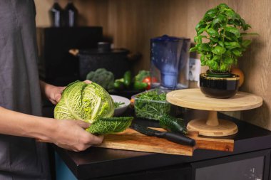 Genç bir çocuk mutfakta elinde lahanayla taze sebze salatası, sağlıklı yaşam tarzı ve ev yemeği konseptini hazırlıyor..
