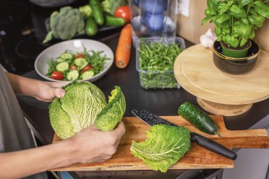 Genç bir çocuk mutfakta elinde lahanayla taze sebze salatası, sağlıklı yaşam tarzı ve ev yemeği konseptini hazırlıyor..
