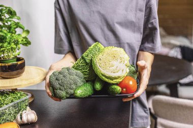Genç çocuk mutfakta bir kase taze sebze salatası tutuyor, sağlıklı bir yaşam tarzı, ev yemeği ve taze yiyecek konsepti..