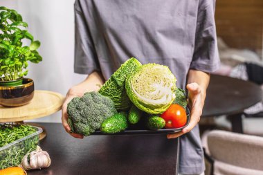 Genç çocuk mutfakta bir kase taze sebze salatası tutuyor, sağlıklı bir yaşam tarzı, ev yemeği ve taze yiyecek konsepti..