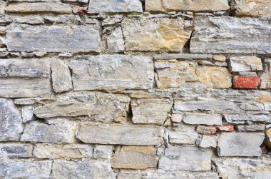 Taştan yapılmış kale duvarı ve farklı şekil ve renklerde tuğlalar.