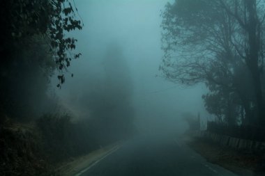 A spooky road passing through Darjeeling on a foggy winter afternoon clipart
