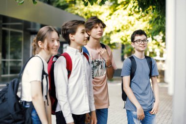 Okul arkadaşları okulun önündeki zaman çizelgesine bakıyor.