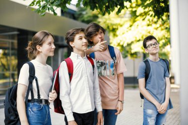 Okul arkadaşları okulun önündeki zaman çizelgesine bakıyor.