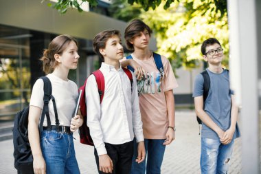 Okul arkadaşları okulun önündeki zaman çizelgesine bakıyor.