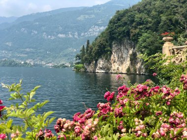 İtalya 'daki Como Gölü' nün dağ, göl ve çiçek manzaralı güzel bir göl manzarası. Fotoğraf Villa Del Balbianello, Lenno İtalya 'da çekildi..