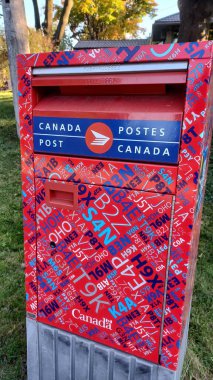 Toronto, ON, Kanada - 5 Ekim 2025: Kanada Posta Kutusunun kırmızı ve mavi tasarımı ve iki dilli Kanada Posta logosu