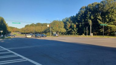 Charlotte, NC, ABD - 10 Ekim 2025: Arabalar gökyüzü altında trafik ışıklarıyla geniş bir şehir kavşağından geçiyor.