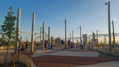 Toronto, ON, Kanada - 13 Ekim 2025: Toronto 'daki Biidaasige Park' ta ahşap yapıları olan bir şehir parkı ve insanlar renkli bir günbatımının keyfini çıkarıyorlar..