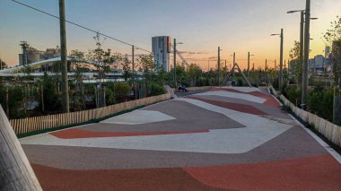 Toronto, ON, Kanada - 13 Ekim 2025: Toronto 'daki Biidaasige Park' ta ahşap yapıları olan bir şehir parkı ve insanlar renkli bir günbatımının keyfini çıkarıyorlar..