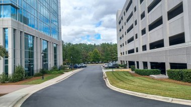 Charlotte, NC, ABD - 30 Eylül 2025: Modern ofis binaları yeşil çimenler, ağaçlar ve Ballantyne Corporate Park 'ta bir yürüyüş yolu arasında duruyor.