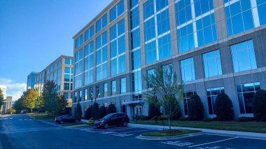 Charlotte, NC, ABD - 30 Eylül 2025: Modern ofis binaları yeşil çimenler, ağaçlar ve Ballantyne Corporate Park 'ta bir yürüyüş yolu arasında duruyor.