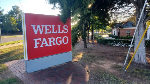 Charlotte, NC, USA - October 10, 2025: Large red Wells Fargo sign stands near a road and trees on a sunny autumn afternoon