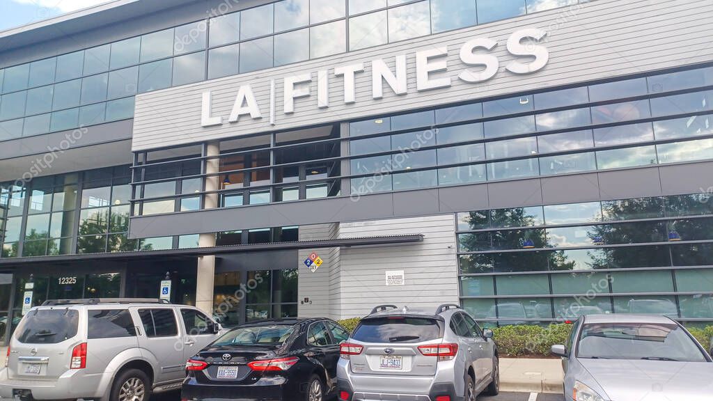 Charlotte, NC, USA - October 2, 2025: The modern glass exterior of an LA Fitness gym building features large letters and parked cars in the foreground.