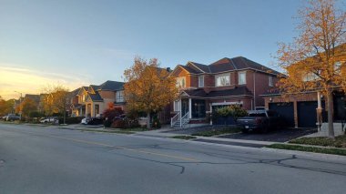 Toronto, Kanada - 15 Ekim 2025: Günbatımında sakin bir yerleşim bölgesinde güz ağaçları olan modern banliyö evleri görülüyor