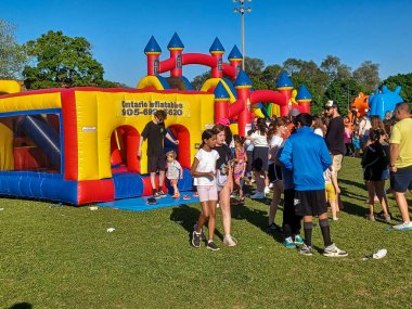 Toronto, ON, Kanada 31 Mayıs 2024: Aileler güneşli bir öğleden sonra bir çocuk etkinliğinde büyük şişme slaytlar ve engelli parkurların etrafında toplandılar..